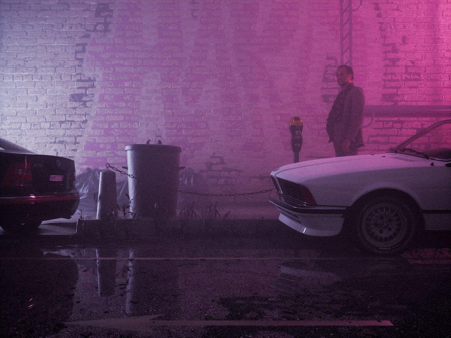 a man standing next to a white car in a parking lot